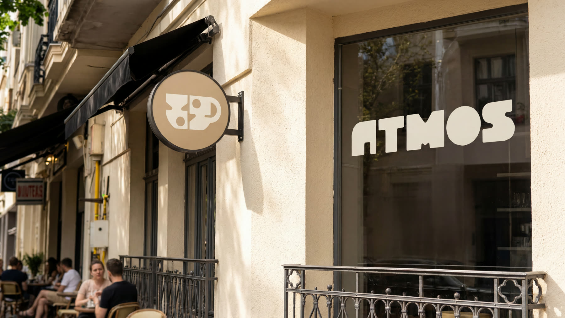 Cafeneaua Atmos: fațada cu wordmark în vitrină și firma rotundă