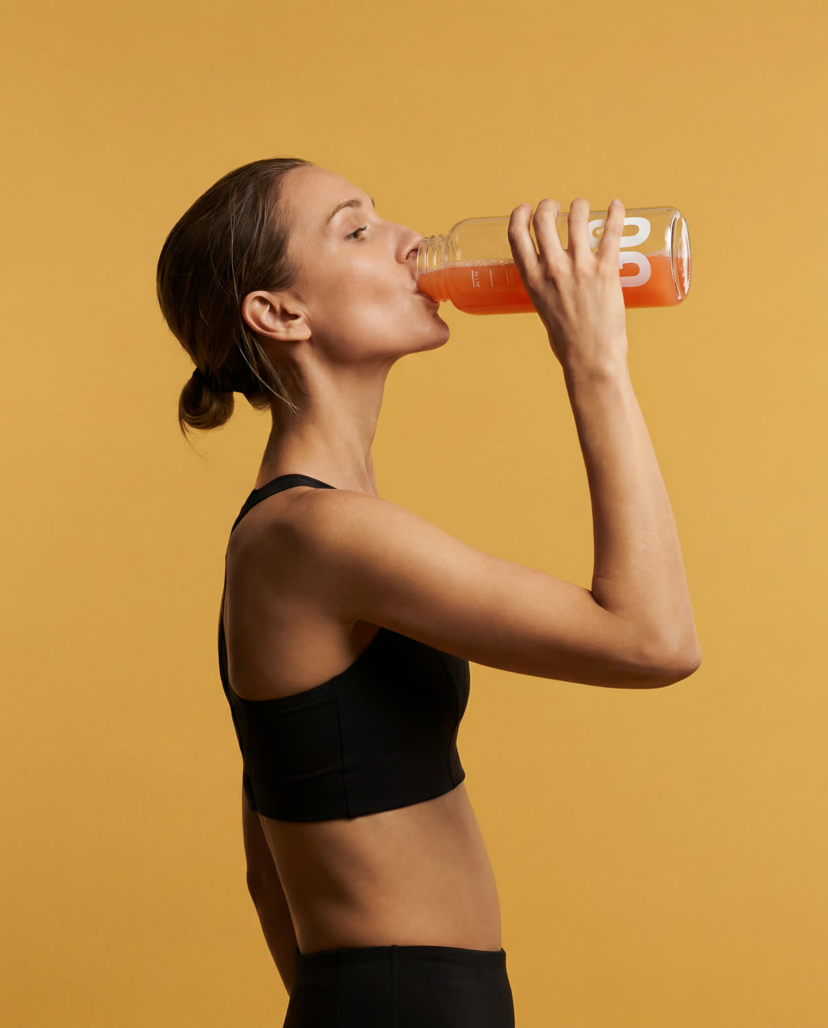 A woman drinking GO against a yellow background